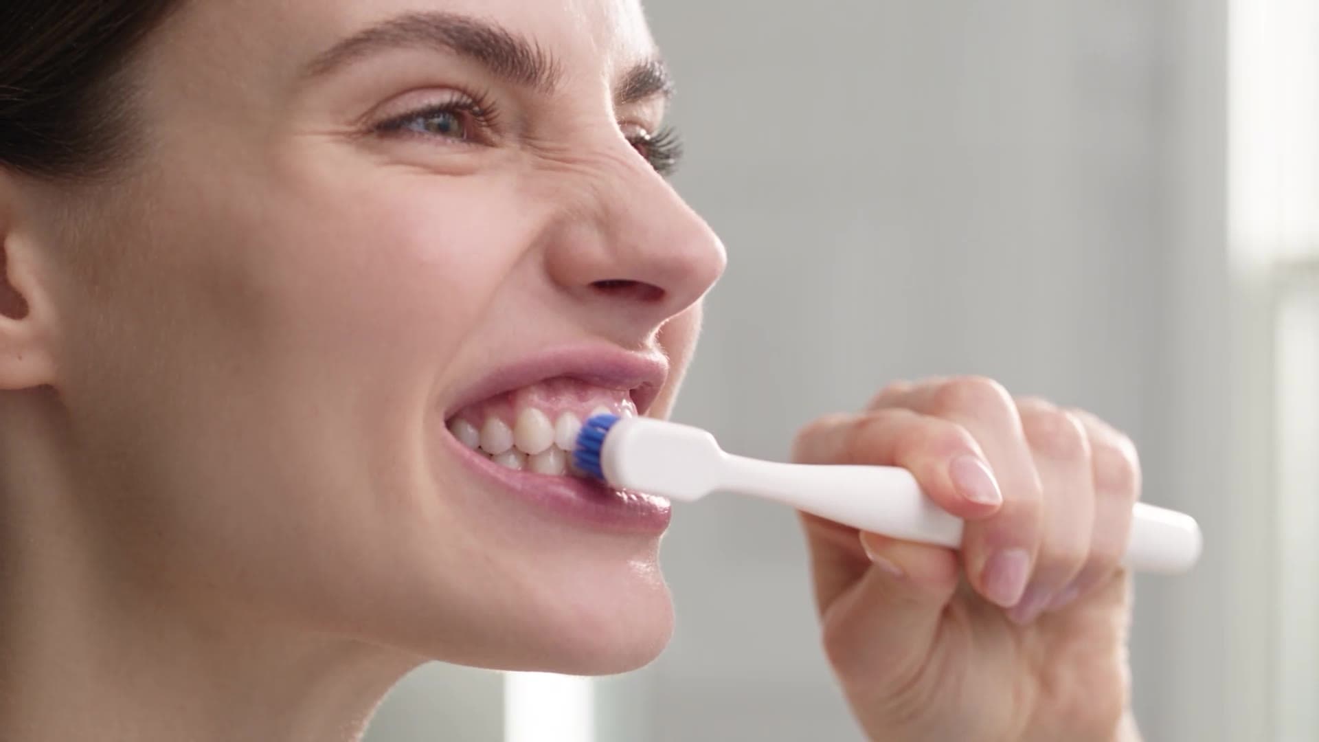 Mulher escovando os dentes com a ADDS Ultra, em primeiro plano